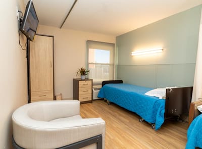 A well-furnished resident room with bed and seating area