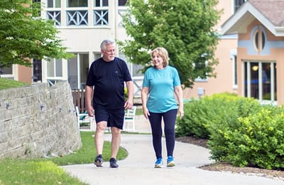 Two residents walking on a path outside the facility