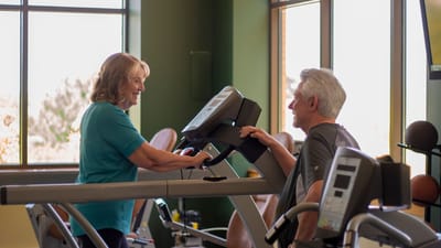 Residents exercising with staff assistance in a fitness area