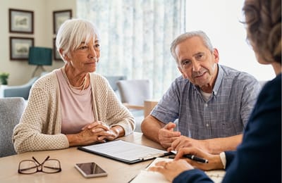 Two seniors consulting with staff in an interior space