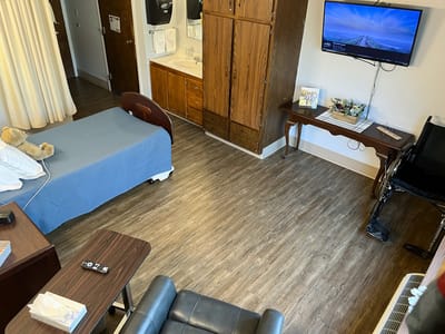 A well-furnished resident room with a bed and TV