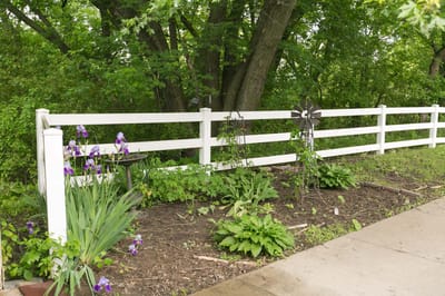 A garden area with flowers and a white fence