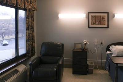 A quiet resident room with a chair and bedside table