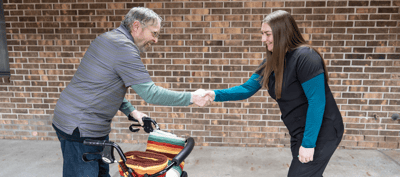 A resident and staff member shaking hands outside