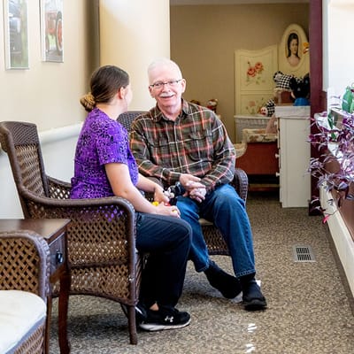 A resident and staff member engaged in conversation in a hallway