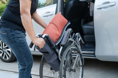 Person assisting with a wheelchair at a vehicle