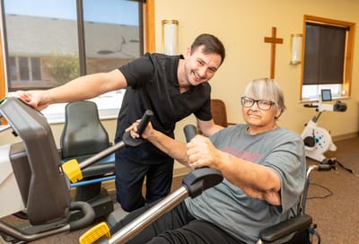 A staff member assisting a resident with exercise equipment