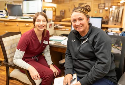Two staff members smiling in a facility office