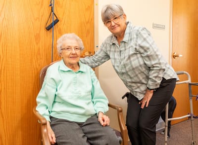 A resident and staff member smiling in an interior setting