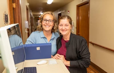 Staff member smiling with a resident in a hallway