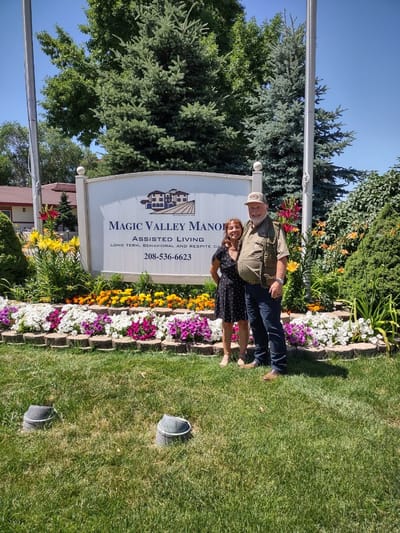 Residents posing in front of Magic Valley Manor sign and flowers