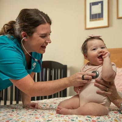 Healthcare worker and baby interacting in a room