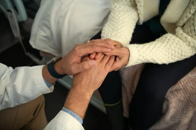 Caregiver holding a resident's hands in a comforting gesture