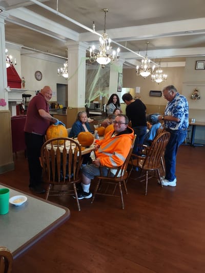 Residents and staff carving pumpkins in a cozy common area