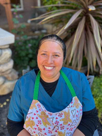 Staff member in apron smiling outdoors