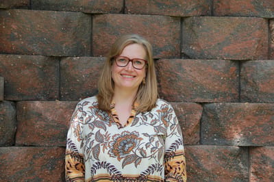 A smiling woman posing in front of a stone wall