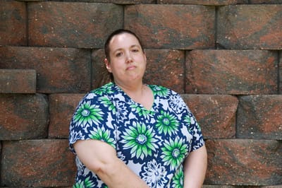 A staff member standing near a stone wall