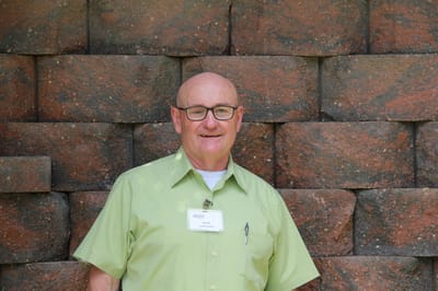 Staff member posing with a brick wall backdrop