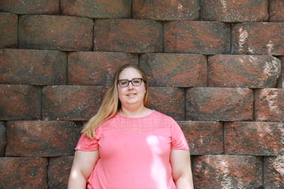 Individual standing against a brick wall outdoors