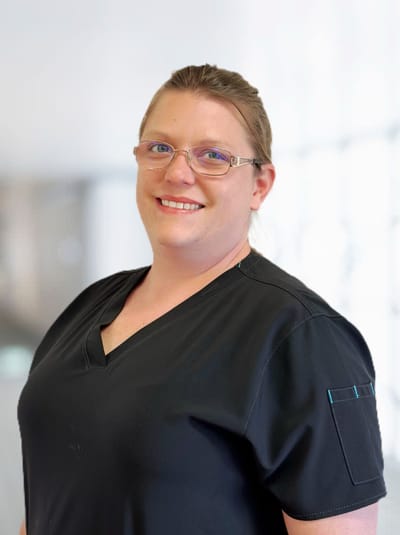 Staff member in nursing facility attire against blurred background