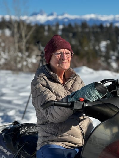 Elderly woman enjoying a snowmobile in a winter landscape