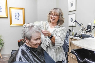 Stylist giving a haircut to a resident in a salon.