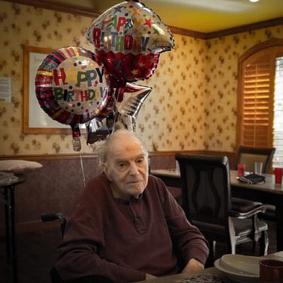 Resident celebrating a birthday with balloons in a common area