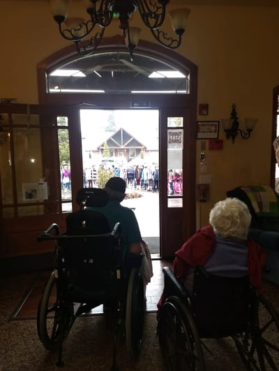 Residents watching an outdoor event from inside the facility