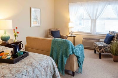 Cozy interior of a resident room with a bed and seating area