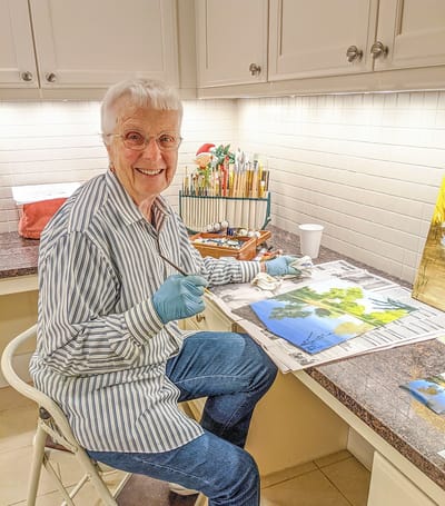 Resident painting at a craft station in a bright room
