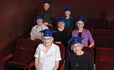 Residents celebrating with graduation caps in a theater