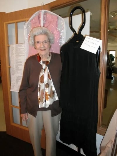 Resident posing with a vintage dress display