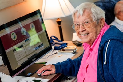 A smiling resident using a computer in a bright room