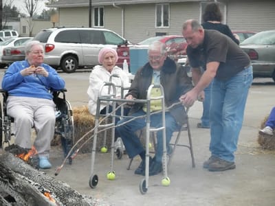 Residents enjoying an outdoor gathering with staff assistance.