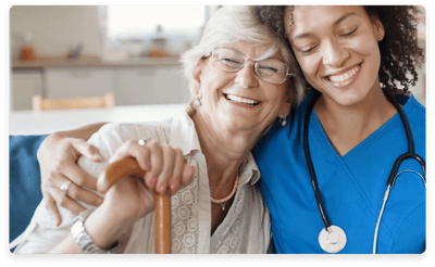 A caregiver and a resident smiling together in a common area