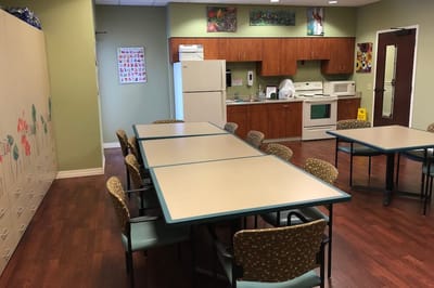 Interior view of a common area with tables and a kitchenette
