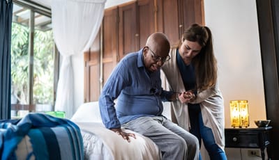 Caregiver assisting elderly man in a bedroom