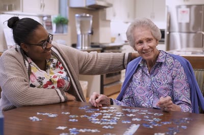 A staff member and resident enjoying a puzzle activity