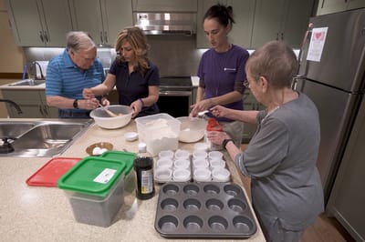 Residents and staff baking together in a kitchen