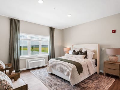 A modern private resident room with a bed and armchairs