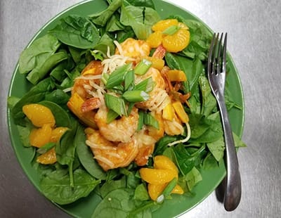 A vibrant meal with shrimp, spinach, and mandarin oranges