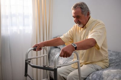 Senior man using a walker in a bright room