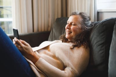 Senior woman enjoying a phone while relaxing on a couch