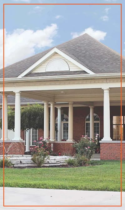 Exterior view of assisted living facility with porch and landscaping