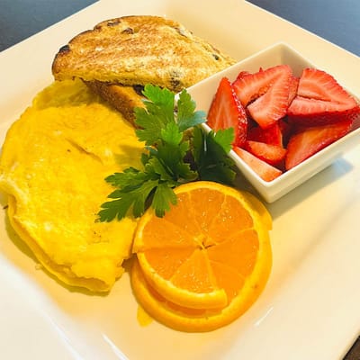A breakfast plate with omelette, toast, and fruit