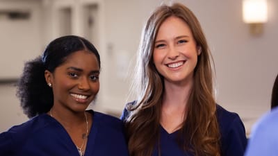 Two staff members smiling in scrubs