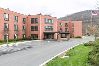 Exterior view of a nursing facility with parking and flags