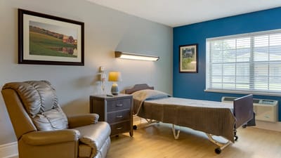A cozy resident room with a bed and chair