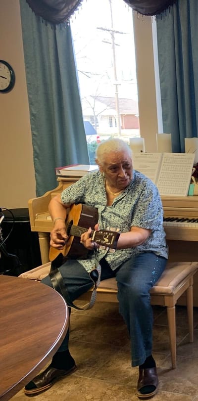 Resident playing guitar in a common area