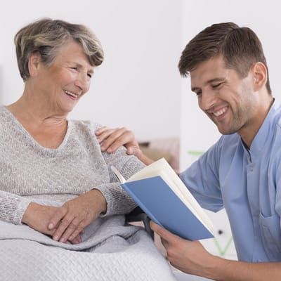 Caregiver reading with an elderly resident in a bright room